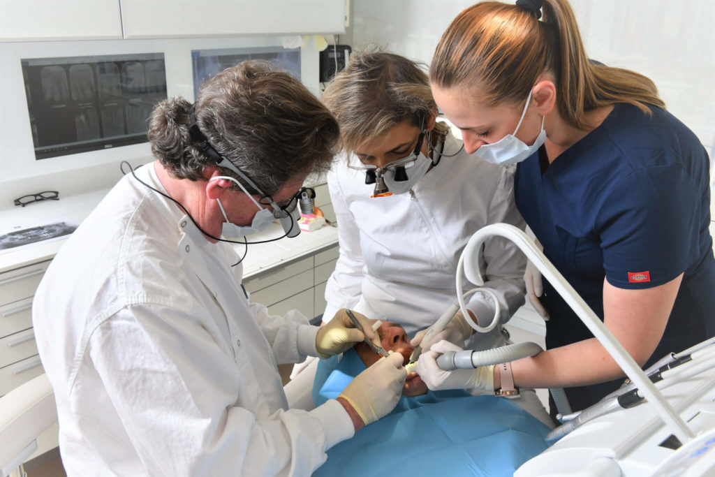 דוקטור מיכל שטיינקלר ופרופסור ארווין וייס שעובדים על שיניים של מטופל.